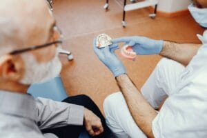 Leczenie bezzębia - dentysta prezentujący starszemu mężczyźnie protezy zębowe
