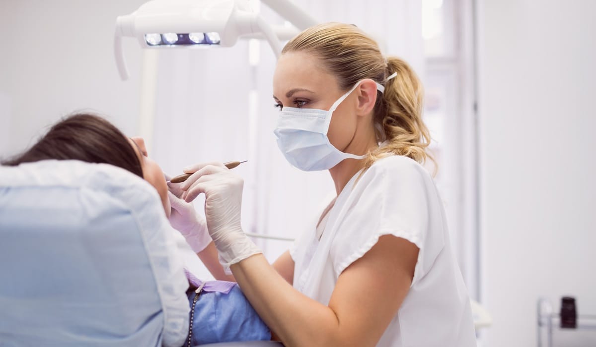 Zmiany w jamie ustnej - dentystka badająca pacjentkę
