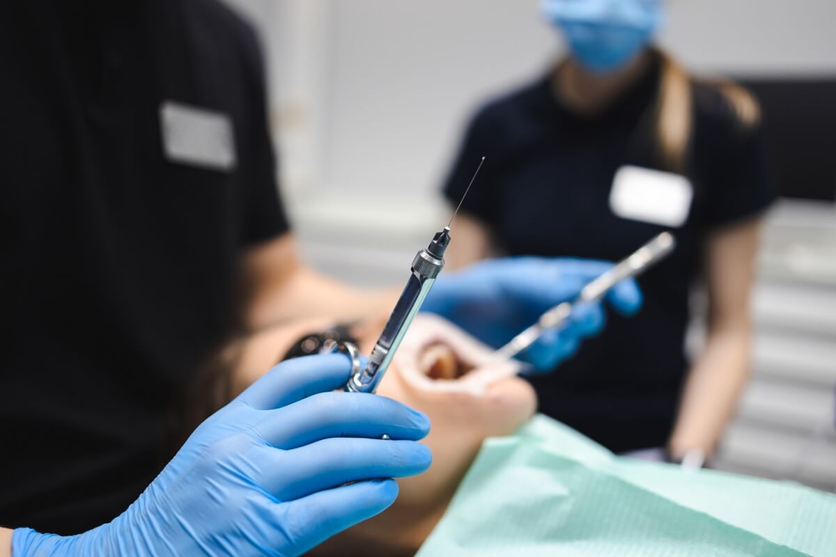 Czy znieczulenie u dentysty boli - dentysta trzymający strzykawkę ze znieczuleniem
